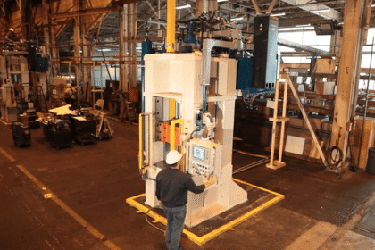 Operator running compact hydraulic forge press for sale on factory floor